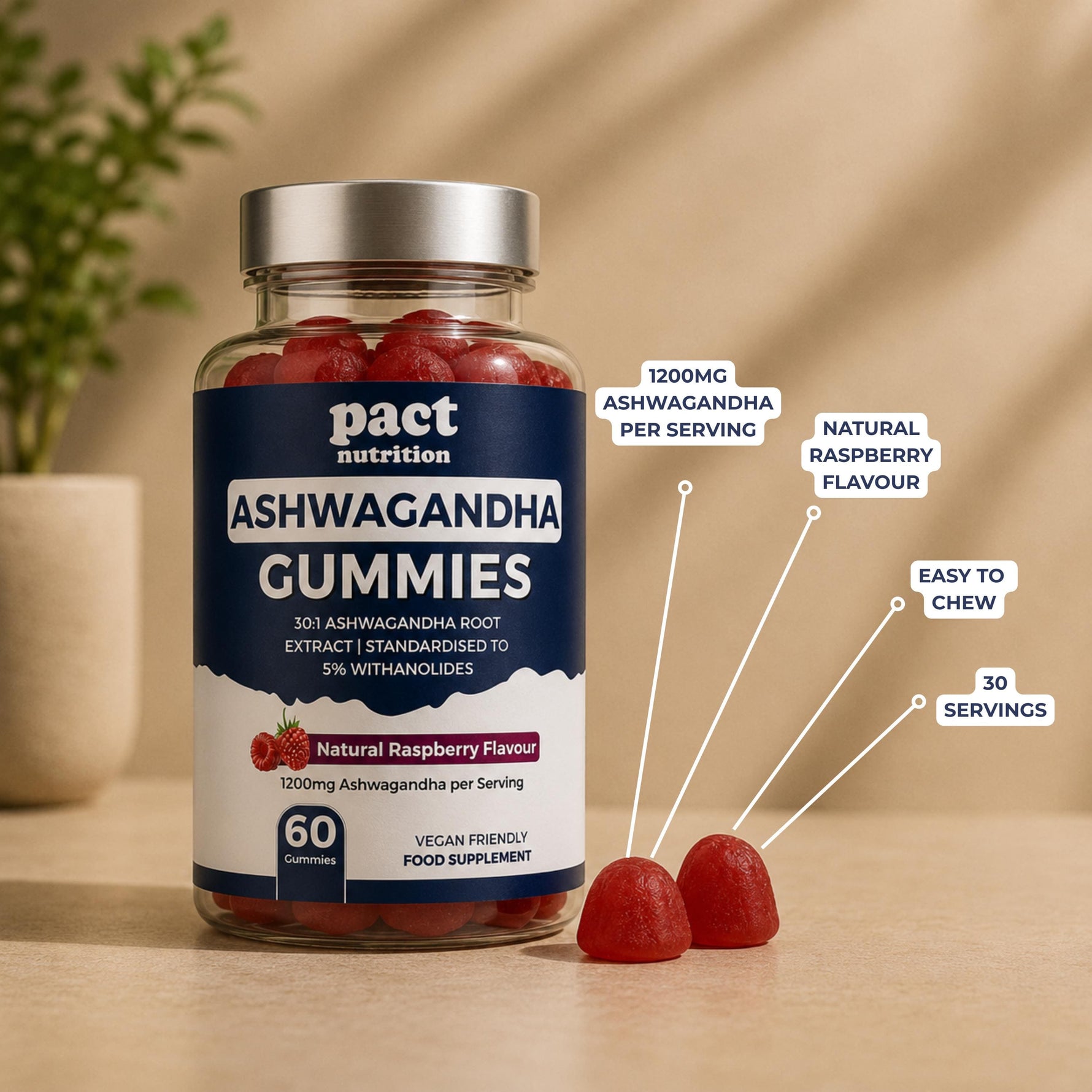 A bottle of Pact Nutrition Ashwagandha Gummies in natural raspberry flavour, shown on a wooden surface with two loose gummies in front. White callout lines with text highlight key features: 1200mg ashwagandha per serving, natural raspberry flavour, easy to chew, and 30 servings