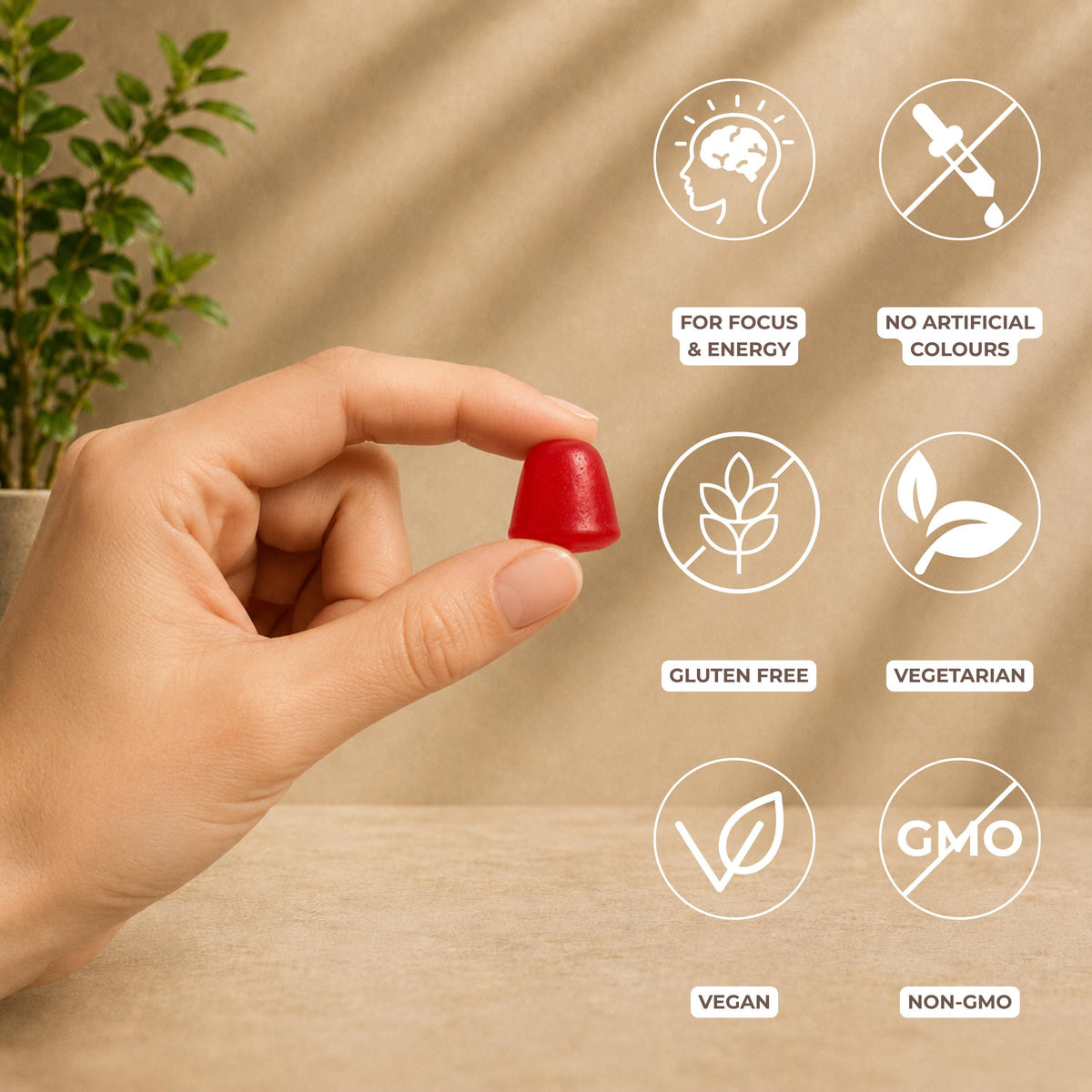 A hand holds a small red gummy against a warm beige background with soft leaf shadows. White circular icons with brown text highlight product benefits: for focus and energy; no artificial colours; gluten free; vegetarian; vegan; and non-GMO
